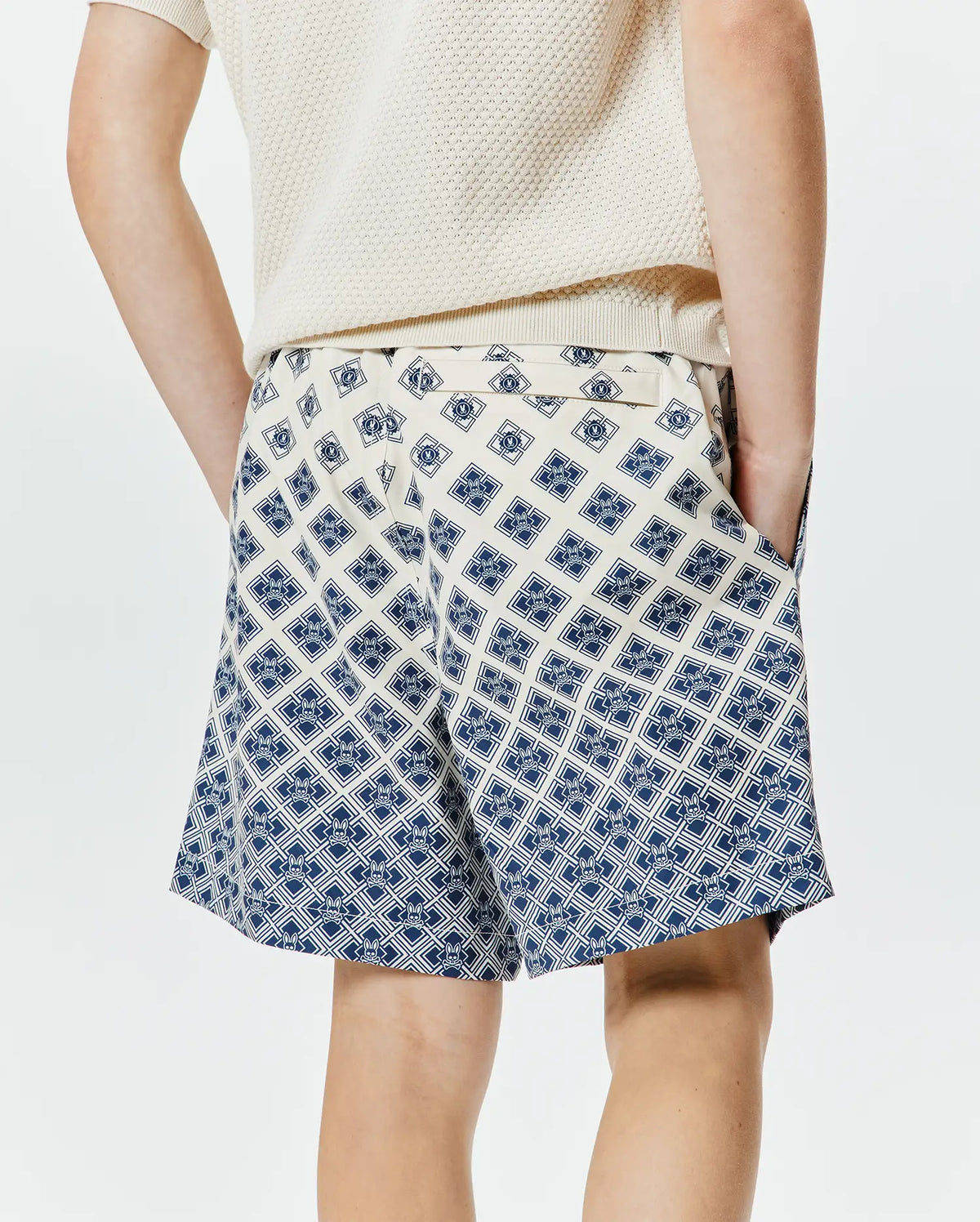 Kids Tobias Swim Trunk, cream with a bold, all-over navy blue geometric pattern featuring the iconic Psycho Bunny skull logo, offering a relaxed fit in smooth, quick-dry fabric. (2)