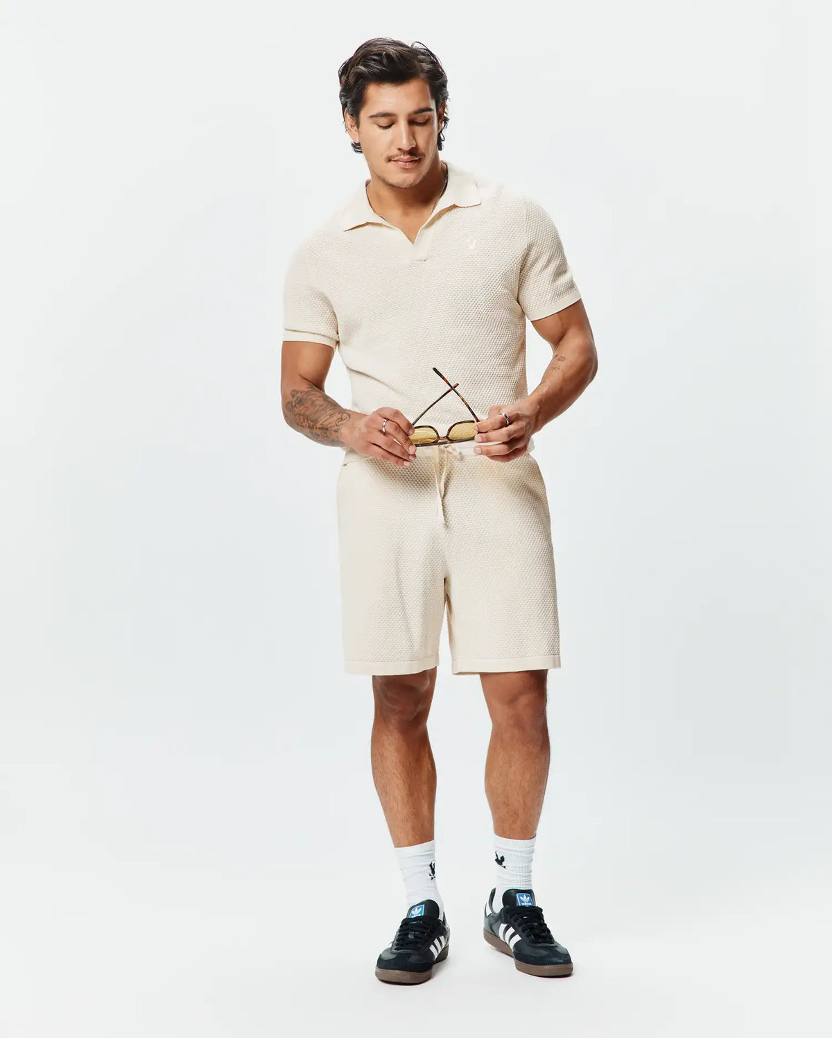 Cream premium textured knit polo with an open collar and small embroidered Psycho Bunny skull logo on the left chest, paired with matching Mens Devon Knit Short with a drawstring waist. (3)