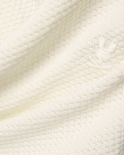 Mens Devon Knit Short in premium cream, featuring a soft, subtly patterned open knit fabric and a small, tone-on-tone embroidered Psycho Bunny skull logo detail. (6)