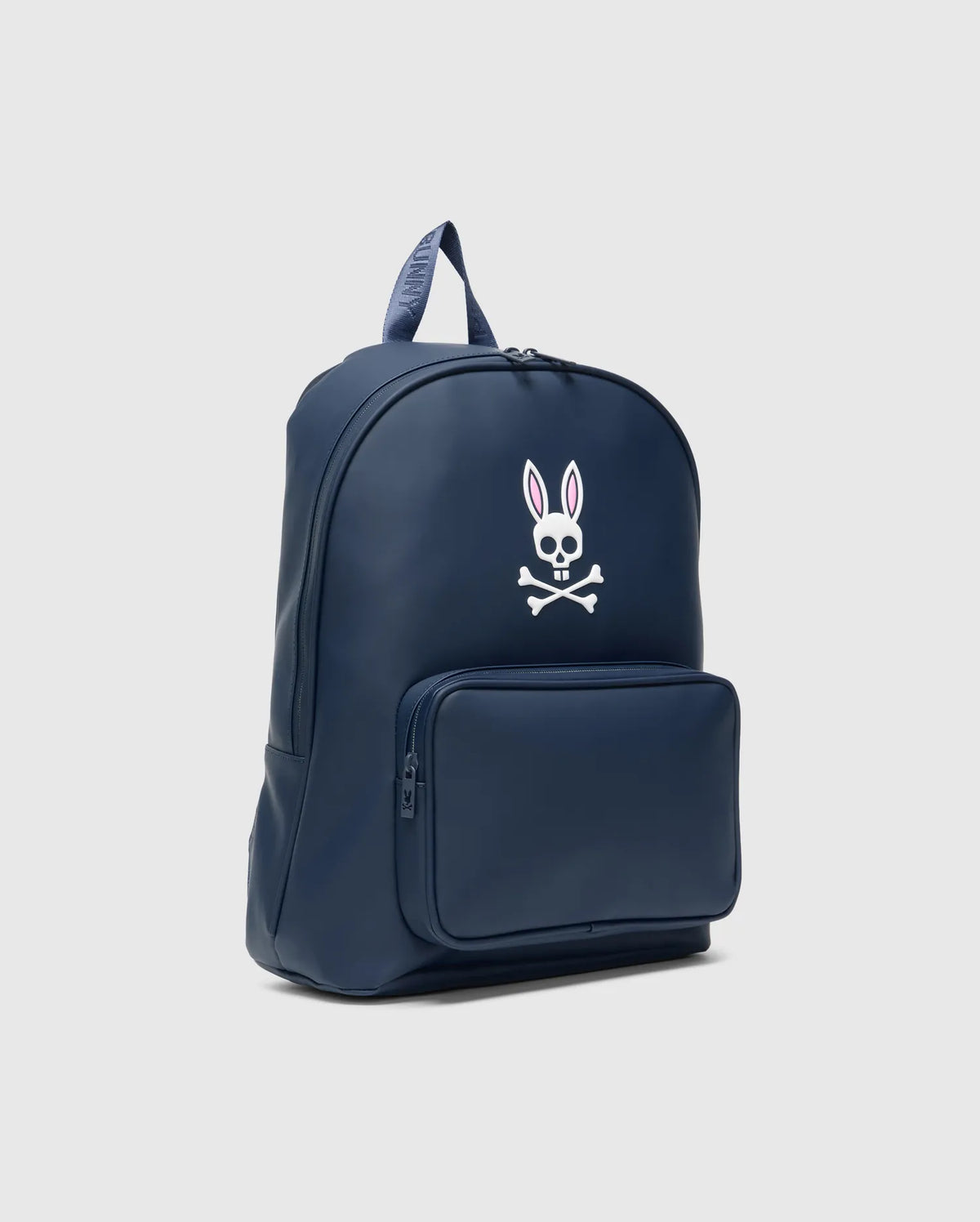 Smooth navy blue Classic Bunny Backpack with a prominent white and pink Psycho Bunny skull logo on the front, a zippered pocket, and a top handle featuring repeated BUNNY text. (1)