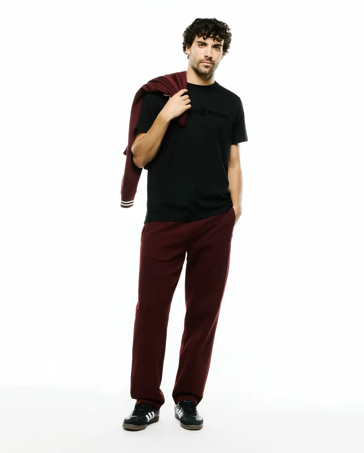 Mens Royce Graphic Tee, a black classic fit jersey t-shirt with a tonal Psycho Bunny chest graphic, paired with relaxed fit maroon french terry sweatpants and a matching sweatshirt with striped cuffs. (5)