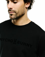 Mens Royce Graphic Tee, a black classic fit smooth jersey knit t-shirt featuring a large tonal black Psycho Bunny text and bunny skull logo across the chest. (3)