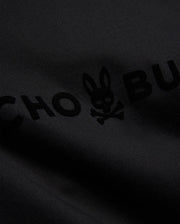 Mens Royce Graphic Tee, a black jersey knit t-shirt featuring a prominent, tonal black velvet-textured Psycho Bunny text and iconic bunny skull logo graphic. (6)