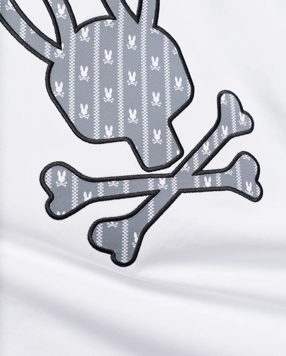 MENS JADEN APPLIQUÉ GRAPHIC TEE featuring a large white jersey fabric with a grey and white patterned bunny skull and crossbones appliqué, outlined in black embroidery. (6)