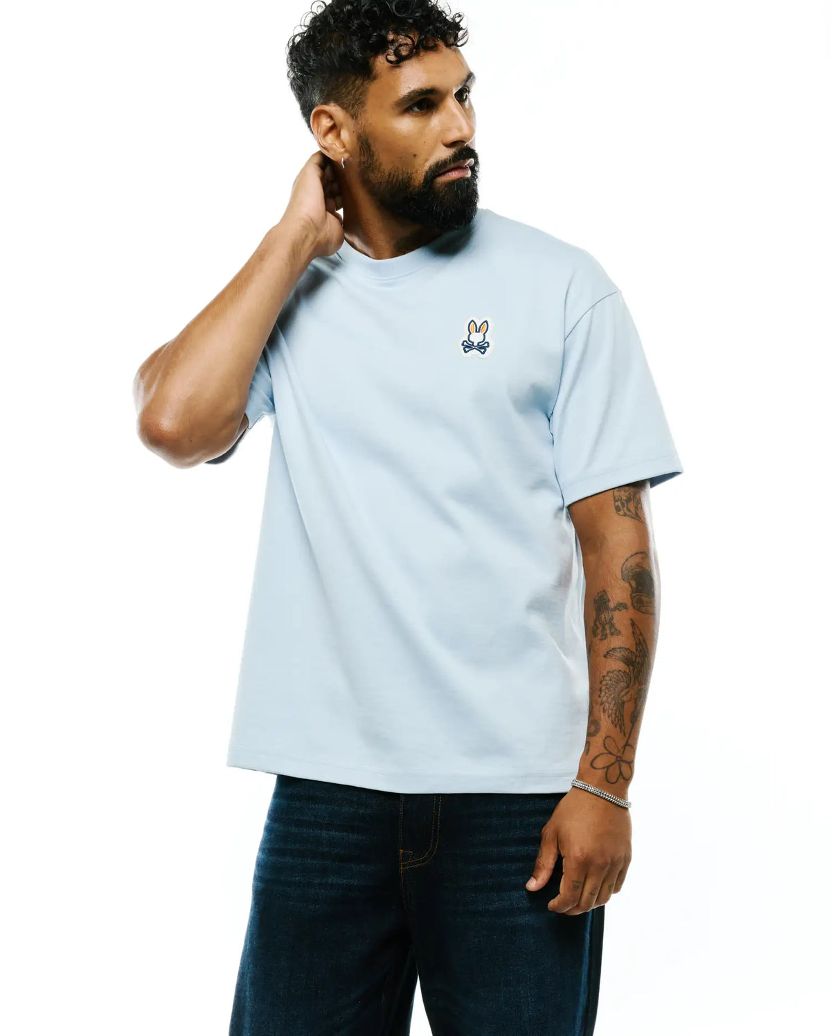Mens Jaydon Pima Cotton Oversized-Fit Tee in light blue, featuring a small embroidered orange, navy, and white Psycho Bunny skull logo on the left chest. Smooth Pima cotton jersey texture. (1)