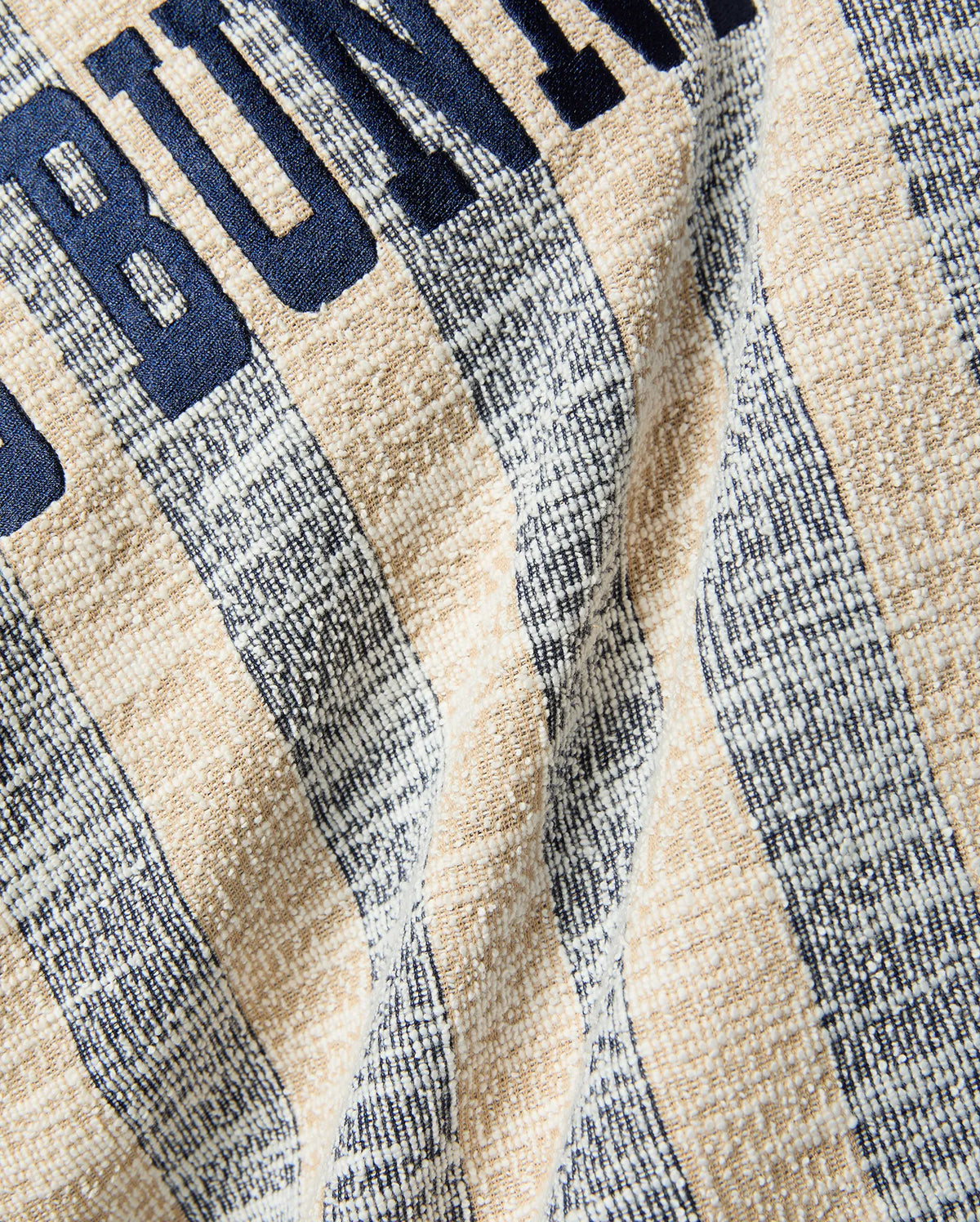 MENS Nathaniel Relaxed Raglan Tee, a relaxed fit textured knit with alternating beige and heathered navy-white vertical stripes, featuring large navy embroidered BUNNY text. (6)