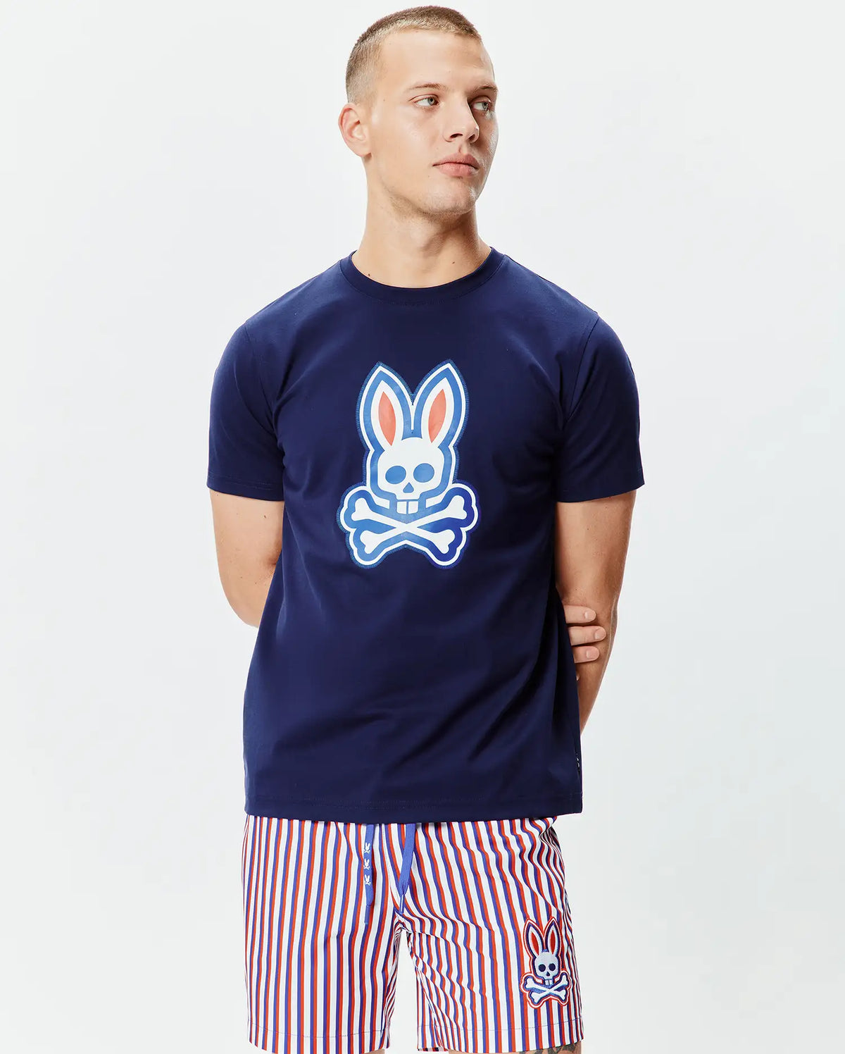 Mens John Graphic Tee, a classic fit navy blue jersey knit t-shirt featuring a large white, light blue, and orange Psycho Bunny skull graphic on the chest and a smaller one on the upper back. (2)