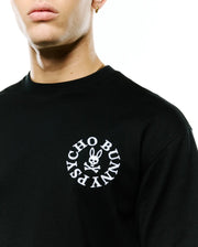 Mens Olek Relaxed Back Graphic Tee, black jersey knit with a relaxed fit, featuring a white embroidered circular Psycho Bunny skull and crossbones logo on the left chest. (2)
