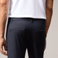 A close-up of a man wearing Psycho Bunny's Men's Gable Regular Fit Sport Pant in dark color and a white t-shirt with orange trim on the sleeves. The focus is on the trousers, showing details like seams.