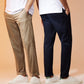 Two men standing close together, viewed from the back. One is wearing Psycho Bunny's men's Gable sport pant and a white shirt, the other navy pants and a white shirt, both in cotton-nylon.