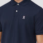 A person wearing a Psycho Bunny MENS CLASSIC POLO - B6K001ARPC made of Pima cotton in dark blue with a small embroidered pink bunny and white crossbones logo on the left side of the chest. The shirt, crafted from diamond-knit piqué fabric, features a collar and buttons, though the person's face is not visible.