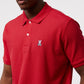 Close-up of a man wearing a red polo shirt with a small Psycho Bunny logo on the left chest area, focusing on the collar and top buttons.