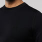 Close-up of a man wearing a black MENS OUTLINE SWEATSHIRT - B6S503ARCN with a small embroidered Psycho Bunny logo on the upper left side. Only the shirt and part of his neck and beard are visible.