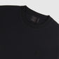 Close-up of a black crew neck T-shirt made from premium textiles, featuring a small embroidered logo of the Psycho Bunny near the hem and a label on the inside collar.
