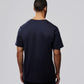 A man with short hair is standing with his back to the camera, wearing a plain, dark navy blue Psycho Bunny MENS OUTLINE TEE - B6U500ARPC made of Pima cotton and dark pants. The background is a solid light gray color.