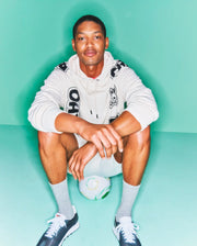 Cream Mens Toby Oversized Hoodie with bold black Psycho Bunny skull and text graphics on chest, sleeves, and hood, featuring a relaxed fit and soft French terry fabric.