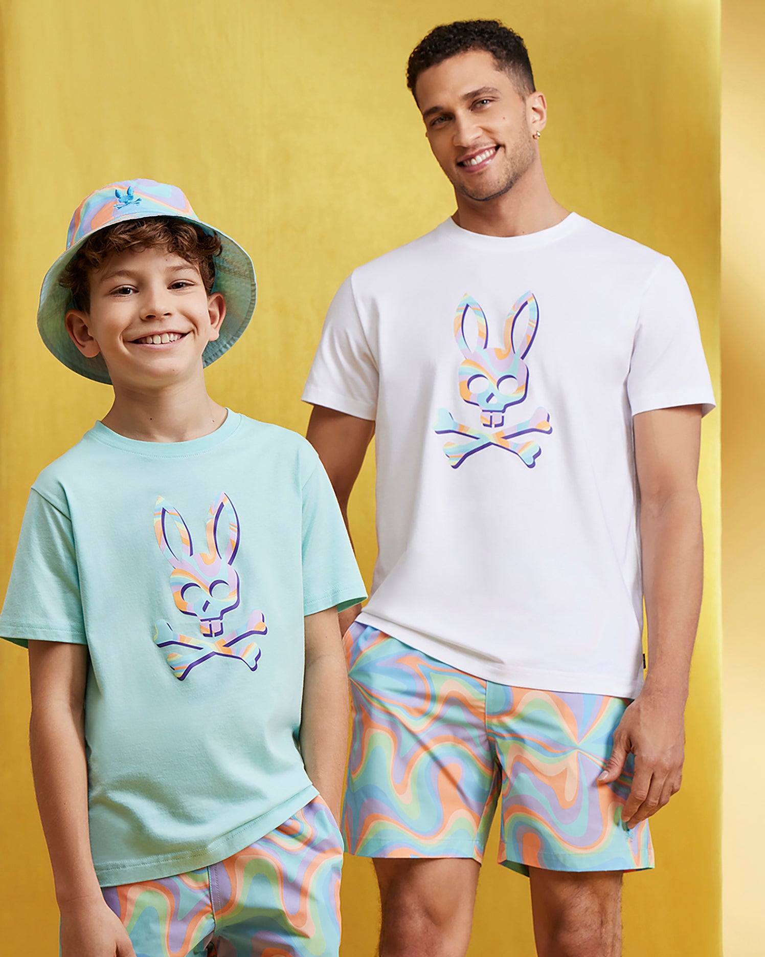 A man and boy, sporting matching Psycho Bunny KIDS BLOOMINGTON SWIM TRUNK - B0W941A2PO, pose for a picture.
