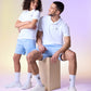 A man and a woman dressed in sporty, casual attire, including the man wearing a Psycho Bunny MENS CLASSIC POLO - B6K001ARPC with a crease-resistant collar and seated on a wooden cube, are posing together. The woman is standing with her