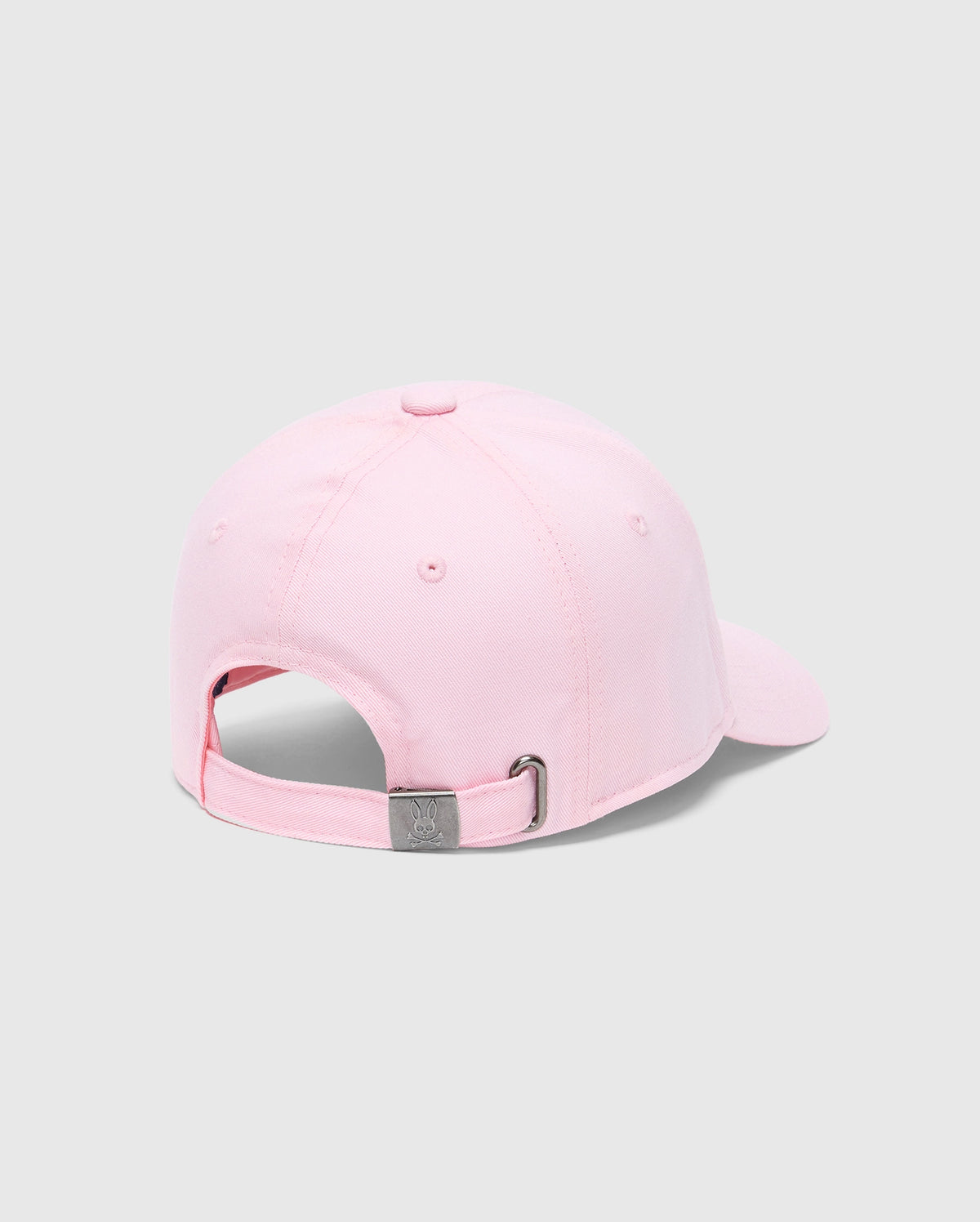 A light pink KIDS CLASSIC BASEBALL CAP - B0A816A1HT by Psycho Bunny is shown from the back, featuring an adjustable fit and sleek metal clasp. The plain light grey background enhances the timeless elegance of this piece.