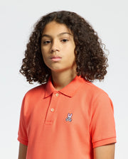 Kids | Kids' hot coral Psycho Bunny classic polo with embroidered logo, ribbed collar, and soft Pima cotton fabric for comfort and style.