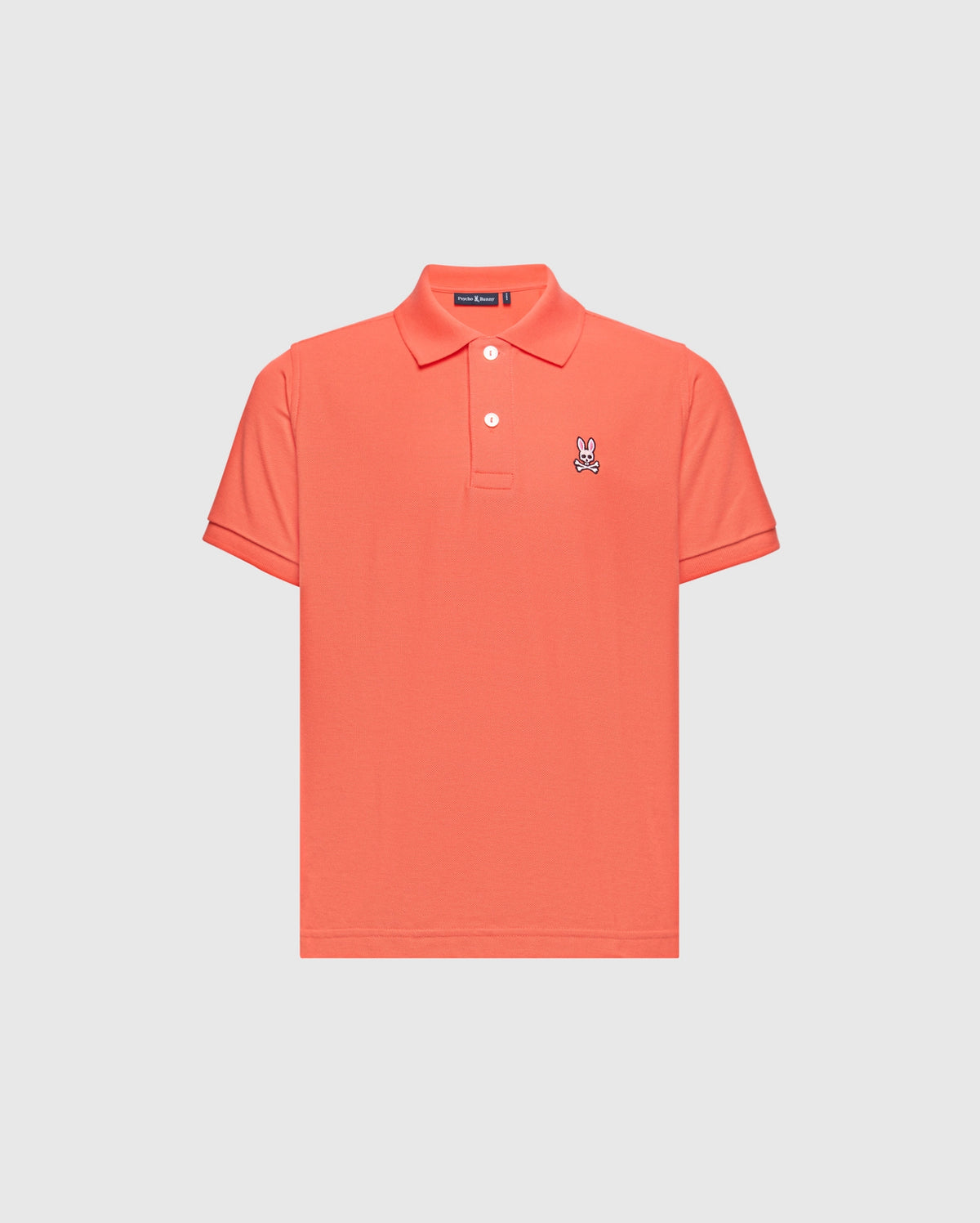 The KIDS CLASSIC PIQUE POLO - B0K001F200 by Psycho Bunny is a coral polo shirt made from premium Pima cotton, featuring short sleeves and a buttoned collar. A small embroidered Bunny logo adds elegance to the left chest on its plain white backdrop.