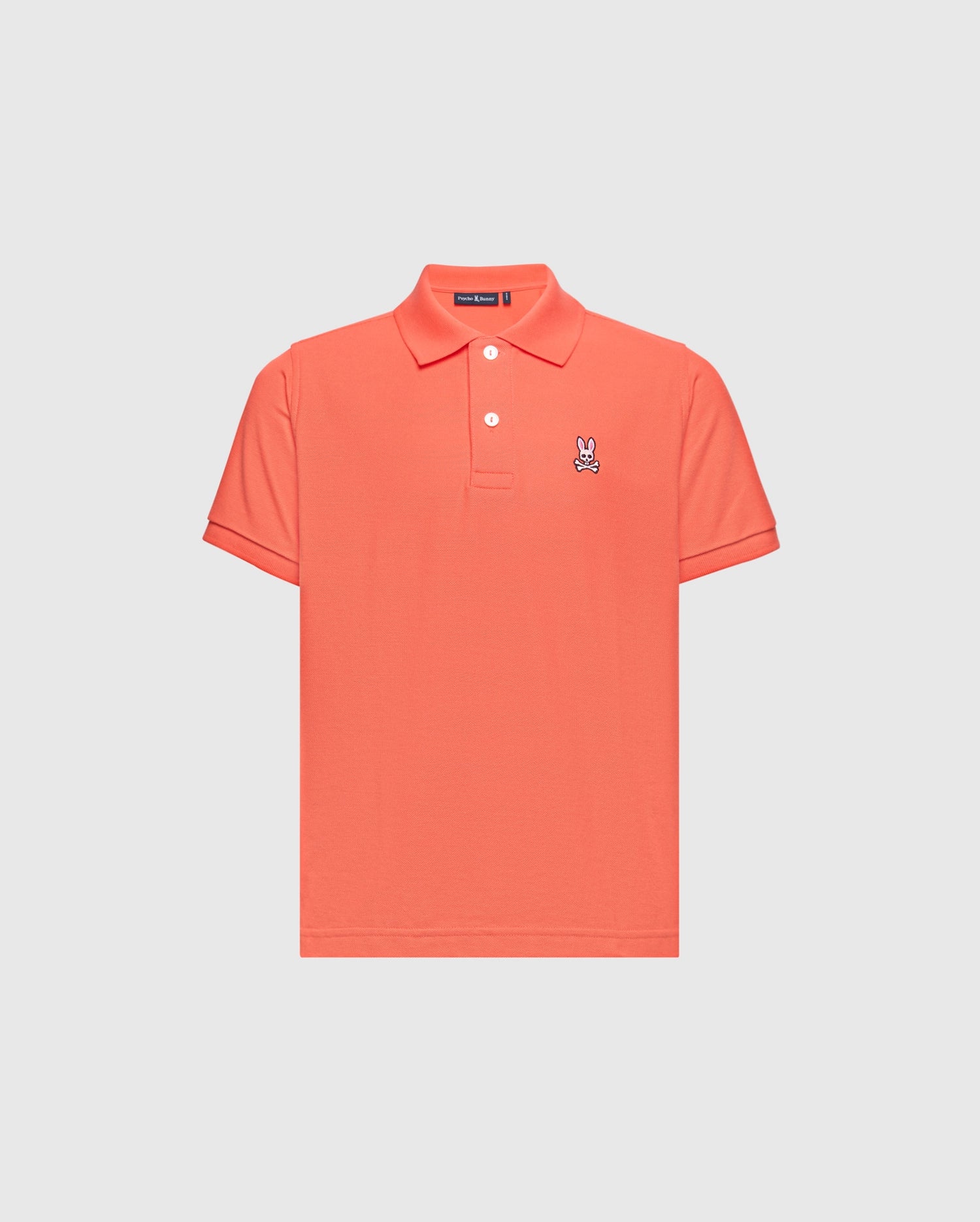 The KIDS CLASSIC PIQUE POLO - B0K001F200 by Psycho Bunny is a coral polo shirt made from premium Pima cotton, featuring short sleeves and a buttoned collar. A small embroidered Bunny logo adds elegance to the left chest on its plain white backdrop.
