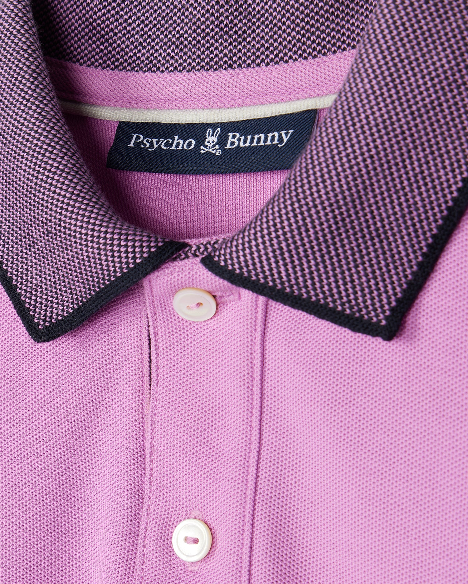 A close-up of a pink Psycho Bunny KIDS SOUTHPORT PIQUE POLO SHIRT - B0K263B200.