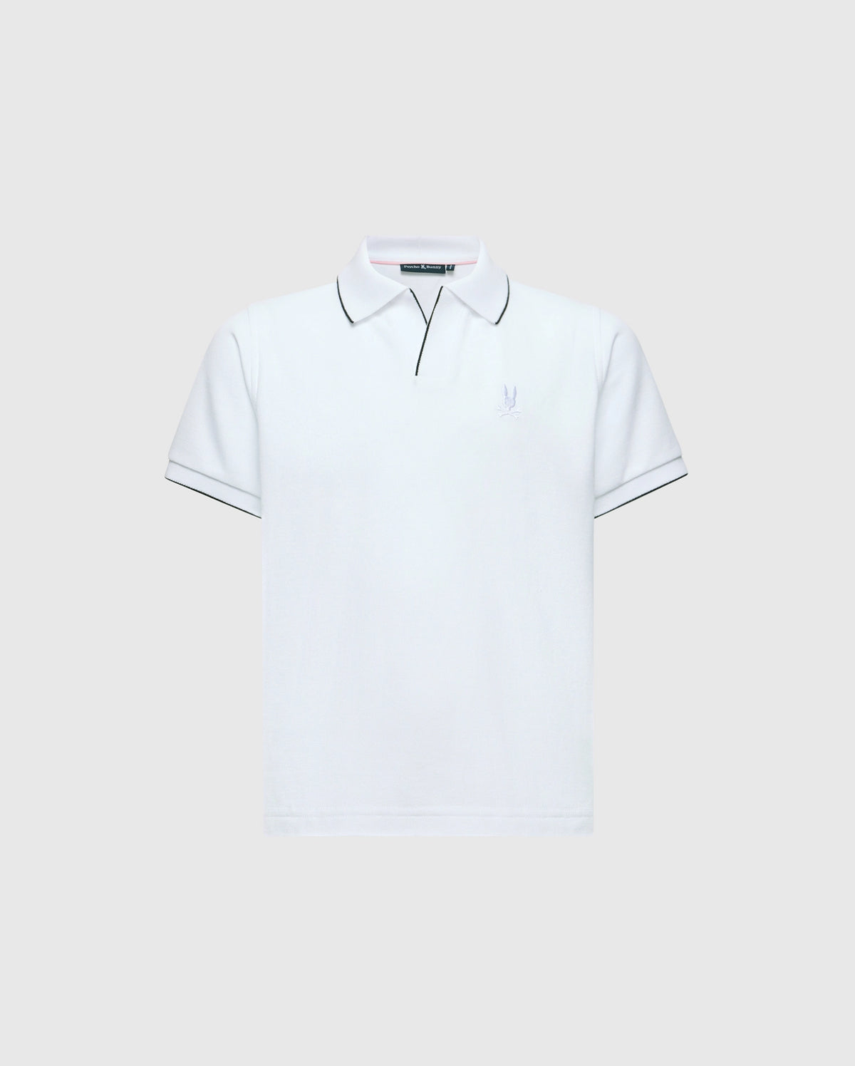 The KIDS EAST HILLS JOHNNY COLLAR POLO - B0K331B200 by Psycho Bunny is a white polo shirt with a Johnny collar and short sleeves set against a gray background. It displays black piping on the collar and sleeves, crafted from soft Pima cotton, featuring a small, subtle seaside-themed logo on the left chest.