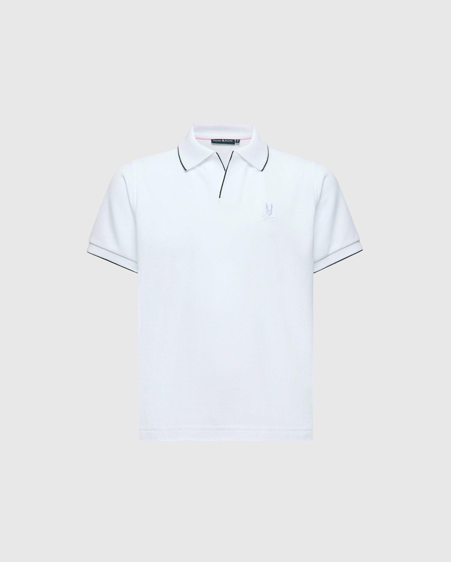 The KIDS EAST HILLS JOHNNY COLLAR POLO - B0K331B200 by Psycho Bunny is a white polo shirt with a Johnny collar and short sleeves set against a gray background. It displays black piping on the collar and sleeves, crafted from soft Pima cotton, featuring a small, subtle seaside-themed logo on the left chest.