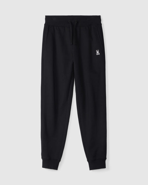 The KIDS LEVY ESSENTIAL FLEECE SWEATPANT - B0P721D200 by Psycho Bunny is a pair of black, 100% cotton sweatpants with an elastic waistband and drawstring, featuring a small white embroidered bunny logo on the left thigh. These cozy playtime pants have cuffed ankles and side pockets, making them ideal for active moments. They are displayed on a plain white background.
