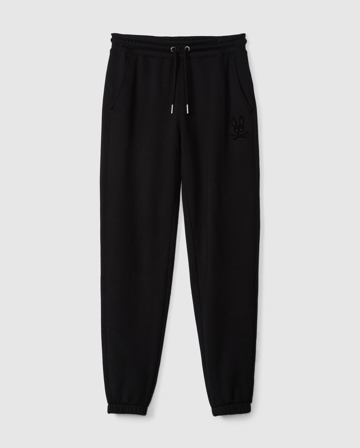 A pair of black Kids Pacific Chenille Jogger pants, designed by Psycho Bunny, featuring an elastic waistband with a drawstring and two side pockets. These joggers have elasticized ankle cuffs and are adorned with a subtle embroidered logo on the upper left side. Displayed against a plain light gray background, this setup perfectly highlights the casual style of these jogger pants.
