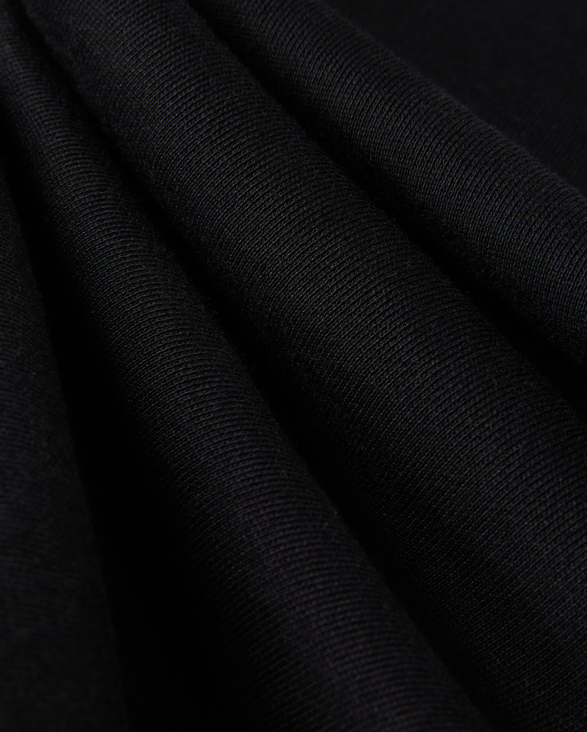 Close-up of folded black fabric with a smooth, textured surface, reminiscent of the KIDS PACIFIC CHENILLE JOGGER - B0P972D200 by Psycho Bunny. The material appears soft and evenly pleated, showcasing its fine fibers and subtle sheen under the light.