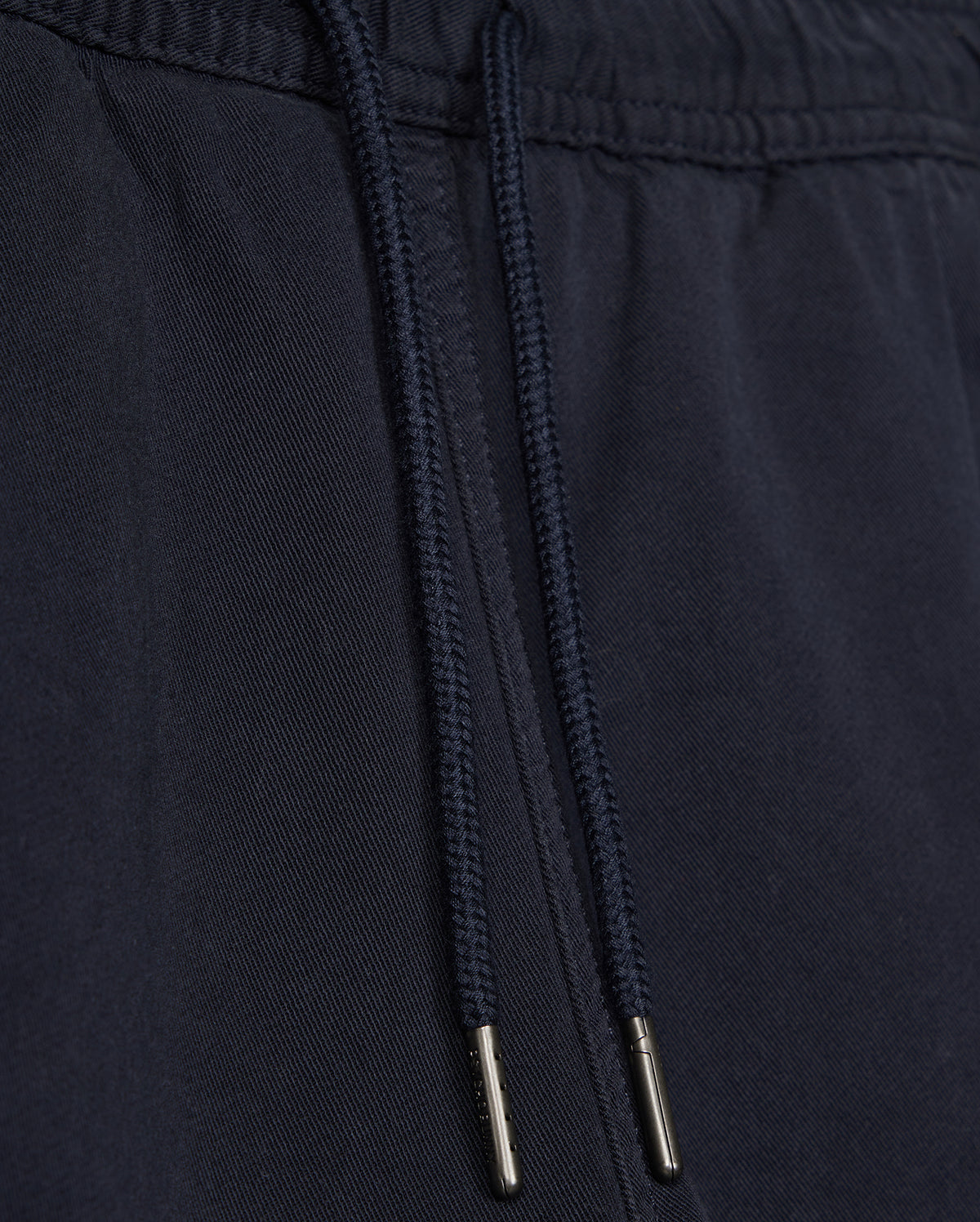 Close-up of a black fabric drawstring with metal aglets on Psycho Bunny's KIDS WILLIS STRETCH TENCEL SHORT - B0R239Y1WB clothing, focusing on the texture and details of the material and drawstring.
