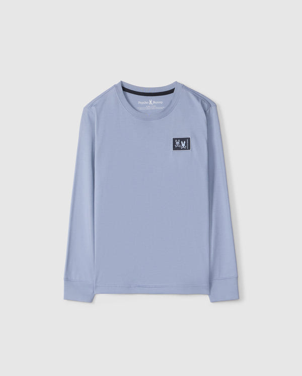 The KIDS MONROE LONG SLEEVE TEE by Psycho Bunny (B0T975D200) is a light blue, regular fit shirt made from soft pima cotton. It has a small black and white logo patch on the left chest, offering versatile comfort, shown on a plain white background.