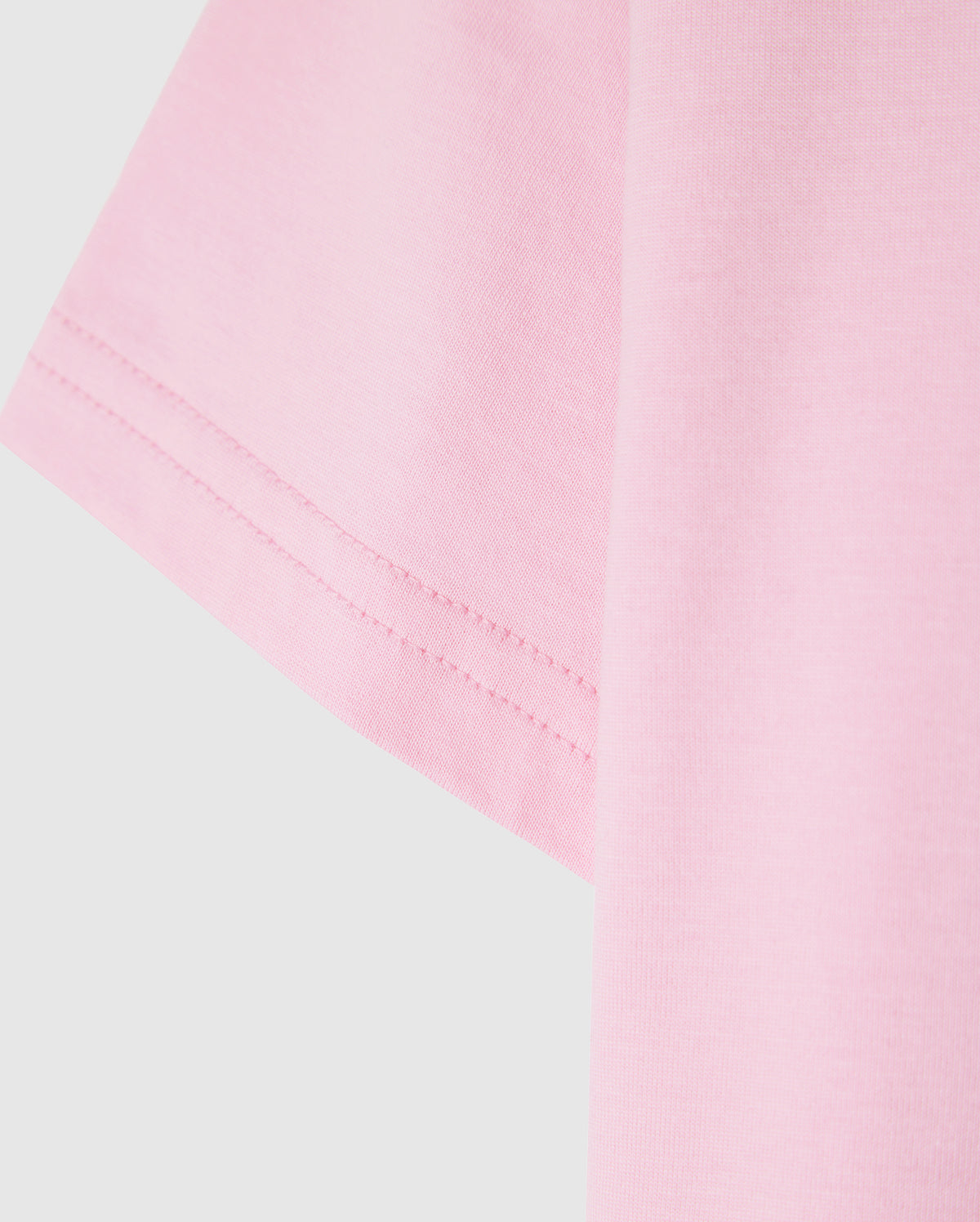 Close-up of the sleeve of a light pink Psycho Bunny KIDS CLASSIC CREW NECK TEE - B0U014CRPC against a plain background, showcasing the 100% Pima cotton fabric texture and stitching detail. An ideal pick for back-to-school outfits.