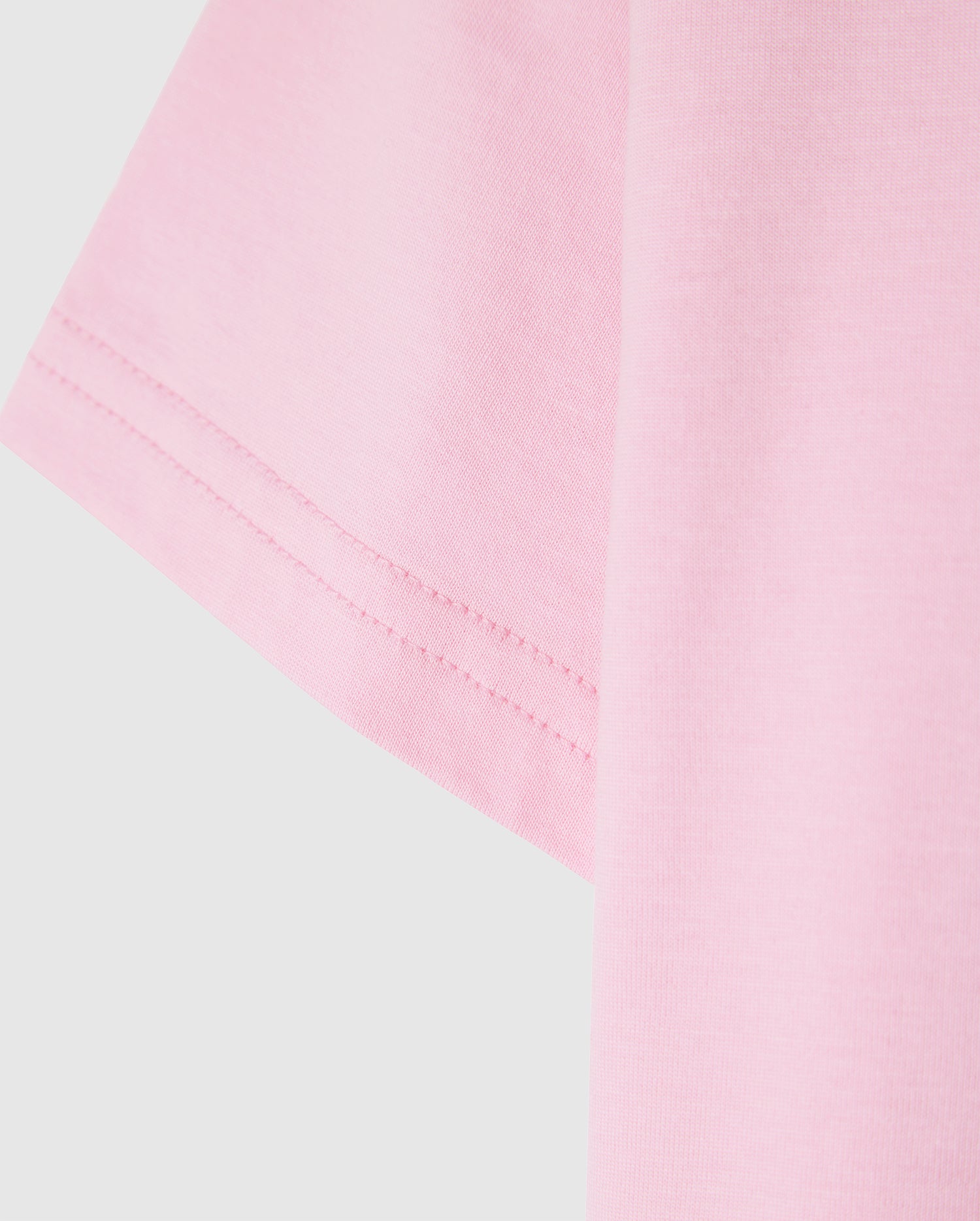 Close-up of the sleeve of a light pink Psycho Bunny KIDS CLASSIC CREW NECK TEE - B0U014CRPC against a plain background, showcasing the 100% Pima cotton fabric texture and stitching detail. An ideal pick for back-to-school outfits.