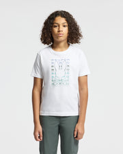 A person with curly hair is wearing the KIDS CORTES GRAPHIC TEE - B0U328E200 by Psycho Bunny, crafted from 100% cotton and showcasing a stylized rabbit graphic, stands against a plain background. They are also wearing dark pants.
