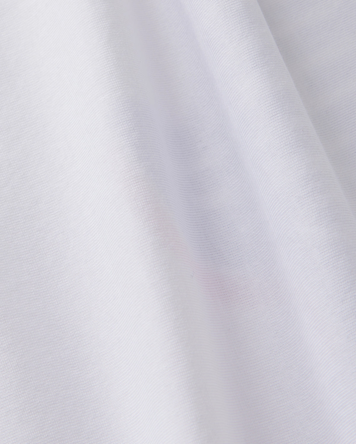 A close-up of the soft, white Peruvian Pima cotton fabric of the KIDS TEXAS CITY TEE - B0U553B2PC by Psycho Bunny shows subtle folds and texture, creating gentle shadows and highlights.