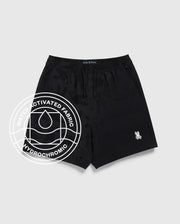 The KIDS PARKER HYDROCHROMIC SWIM TRUNK by Psycho Bunny in black features a subtle camo hydrochromatic pattern, quick-dry fabric, drawstring waistband, and a white logo patch. An overlayed graphic highlights its water-activated fabric. Displayed on light grey.
