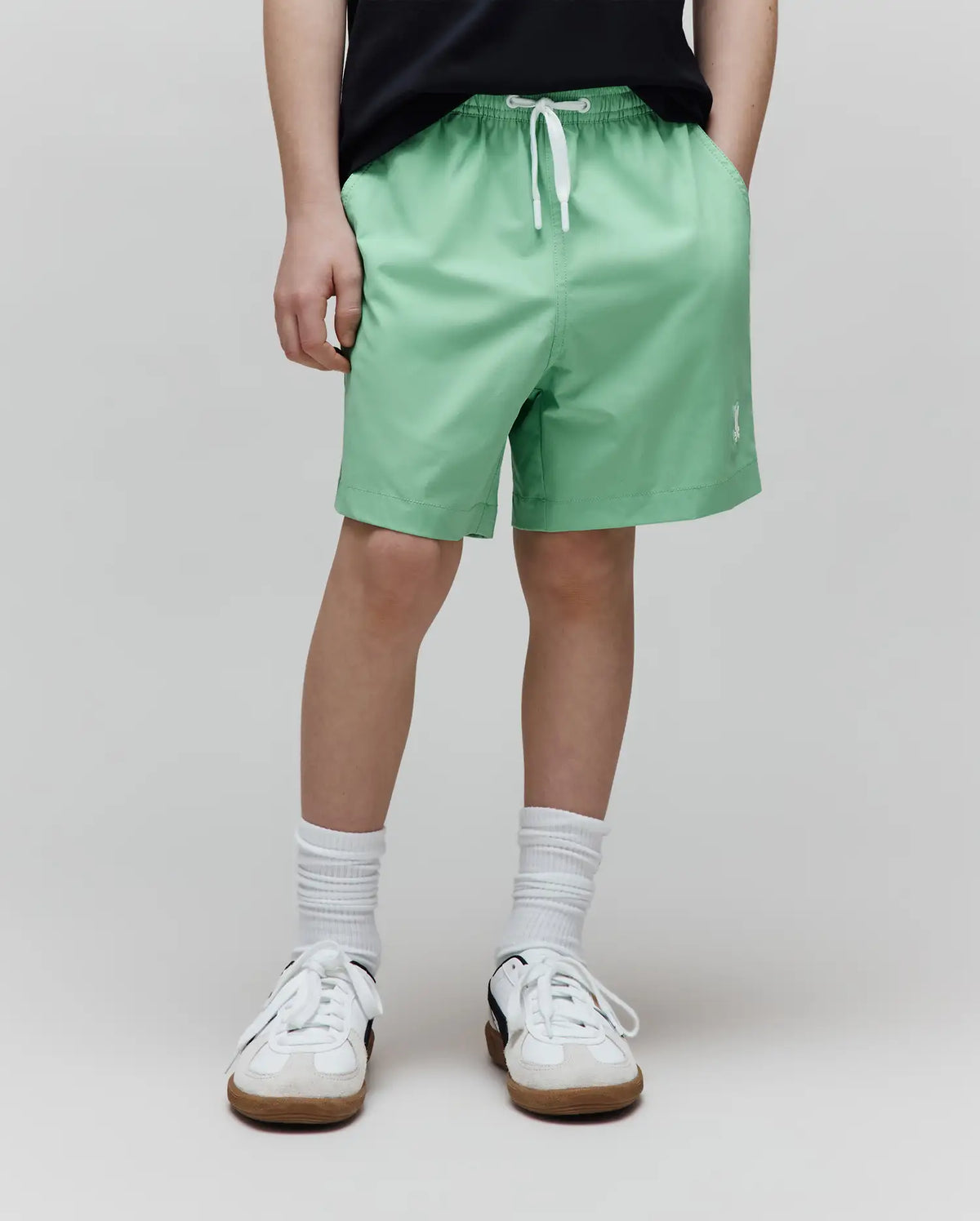 Kids Samos Hydrochromic Printed Swim Trunk, a relaxed fit, mint green short with an elastic waist, white drawstring, and small white embroidered Psycho Bunny skull logo on the left leg.