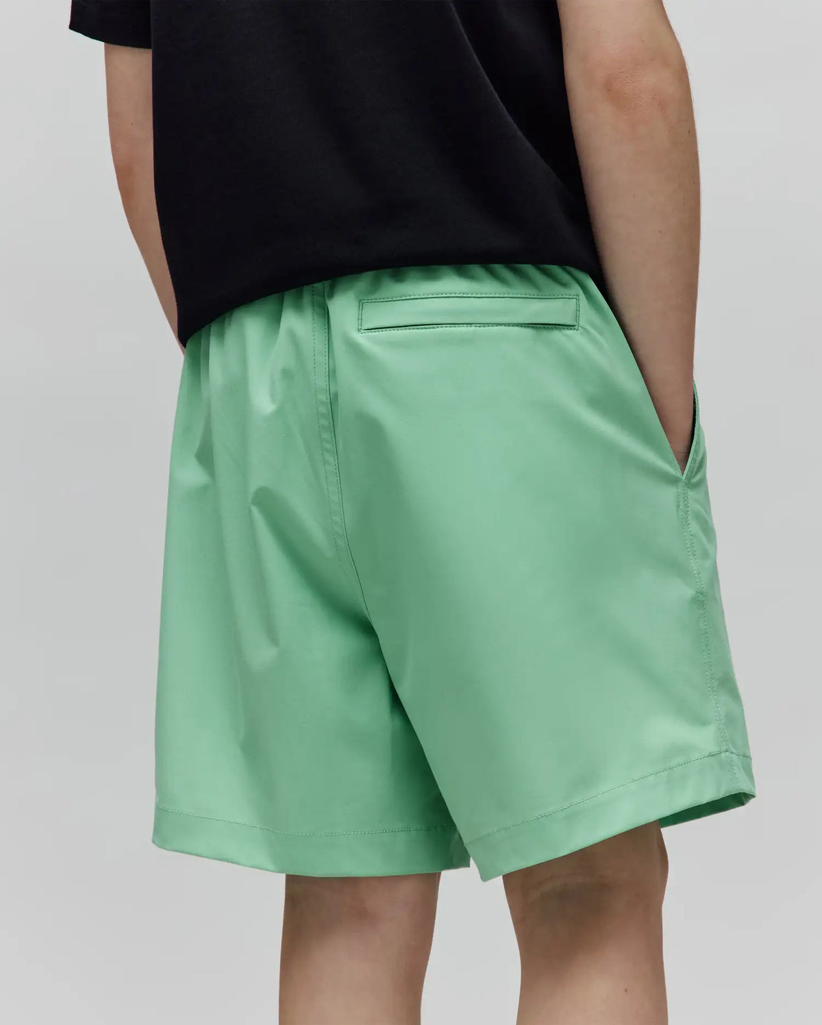 Kids Samos Hydrochromic Printed Swim Trunk in vibrant mint green, featuring a relaxed fit, smooth quick-dry fabric, elastic waistband, side pockets, and a back pocket, from Psycho Bunny.