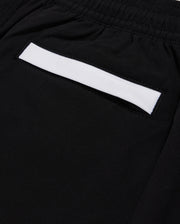 Close-up of Psycho Bunny KIDS PARKER HYDROCHROMIC SWIM TRUNK - B0W646C200 in black, showcasing a small pocket with a white strip above it. The fabric appears smooth and is quick-dry material. The pocket is integrated into the design, suggesting a sleek and minimalistic style.