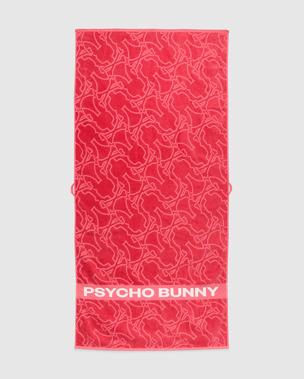A red Psycho Bunny towel, model B6A287F200, is crafted from plush terrycloth cotton. It features abstract bunny designs and a solid red band at the bottom edge with the iconic white "PSYCHO BUNNY" text, merging style and comfort in premium apparel.