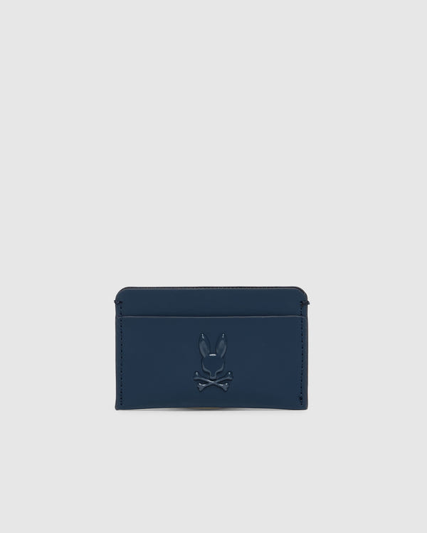 The Psycho Bunny Men's Rubberized Card Case, model B6A473F200 in navy blue, features a raised stylized bunny head with crossbones design. This minimalistic card holder has a single compartment on a plain background to keep your belongings secure in style.