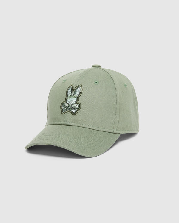 The MENS BAXTER EMBROIDERED BASEBALL CAP - B6A552F200 by Psycho Bunny features light green cotton twill, a curved brim, and an embroidered cartoon bunny head with crossbones on the front for a stylish, luxury fit.