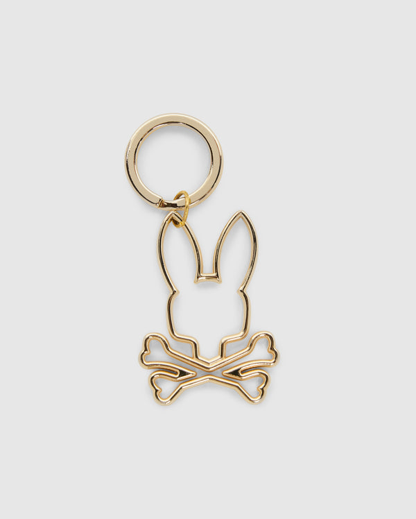 The Psycho Bunny OUTLINE BUNNY KEYCHAIN - B6A565E200 is a gold alloy accessory featuring a minimalist bunny outline with ears up and crossed bones. Its smooth finish enhances its simplicity and elegance.