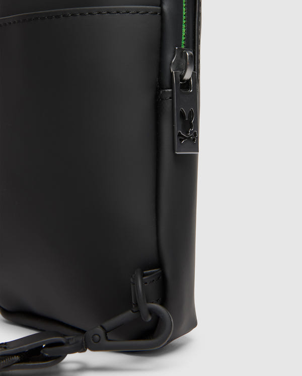 Close-up of the Psycho Bunny MENS RUBBERIZED CROSSBODY - B6A635F200, featuring sleek black leather with a visible zipper and a small rabbit-shaped metal charm. The durable design includes a side clip attachment and hints of green lining peeking by the zipper.