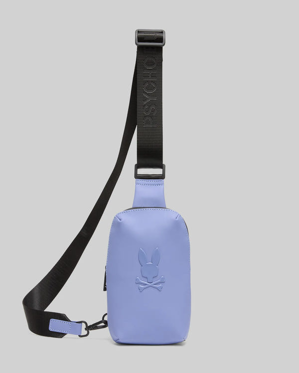 The Psycho Bunny MENS RUBBERIZED CROSSBODY - B6A635F200 is a small lavender polyester bag with an embossed bunny and crossbones logo, plus a wide black adjustable "PSYCHO BUNNY" strap, shown on a light grey background.