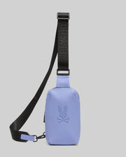The Psycho Bunny MENS RUBBERIZED CROSSBODY - B6A635F200 is a small lavender polyester bag with an embossed bunny and crossbones logo, plus a wide black adjustable "PSYCHO BUNNY" strap, shown on a light grey background.