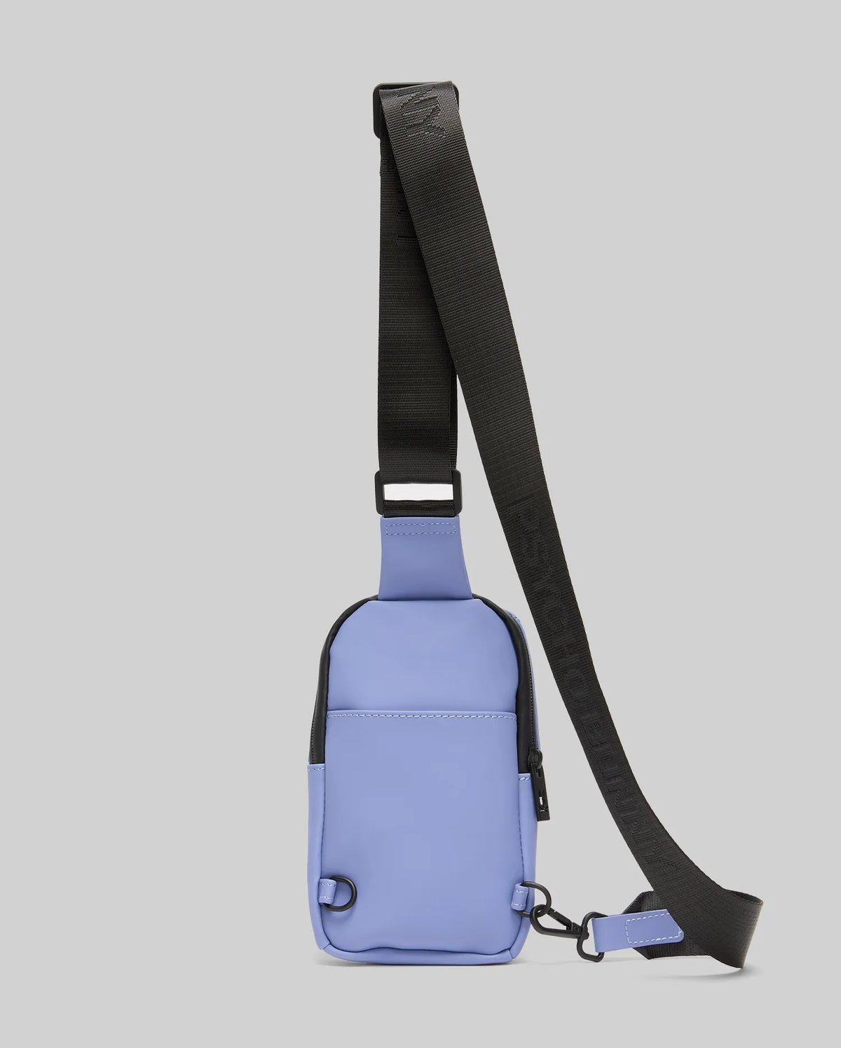 The Psycho Bunny MENS RUBBERIZED CROSSBODY - B6A635F200 is a compact, rectangular light purple bag in durable polyester with a wide, adjustable black strap and zipper, shown upright on a plain light gray background.